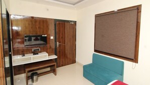 Una habitación moderna con un mueble de televisión de madera, un sofá azul y una cama roja.