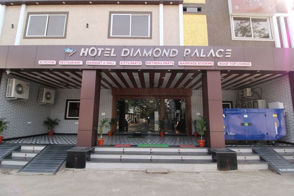 The entrance of Hotel Diamond Palace with a sign listing amenities like an acrooom, restaurant, banquet hall, kitty party, birthday party, marriage booking, and roof top lounge.