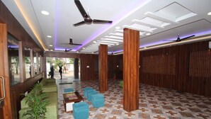 Un hall con piso estampado, asientos verdes y paneles de madera.