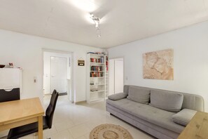 Un salon comprenant un canapé, une table basse, une bibliothèque et une porte donnant sur une autre pièce.