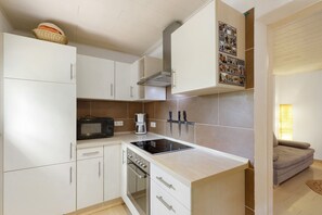 A modern kitchen with white cabinets, a built-in oven, a microwave, and a gas stove. - Apartment 'Maintal  2' with Private Terrace, Private Garden and Wi-Fi (Maintal)