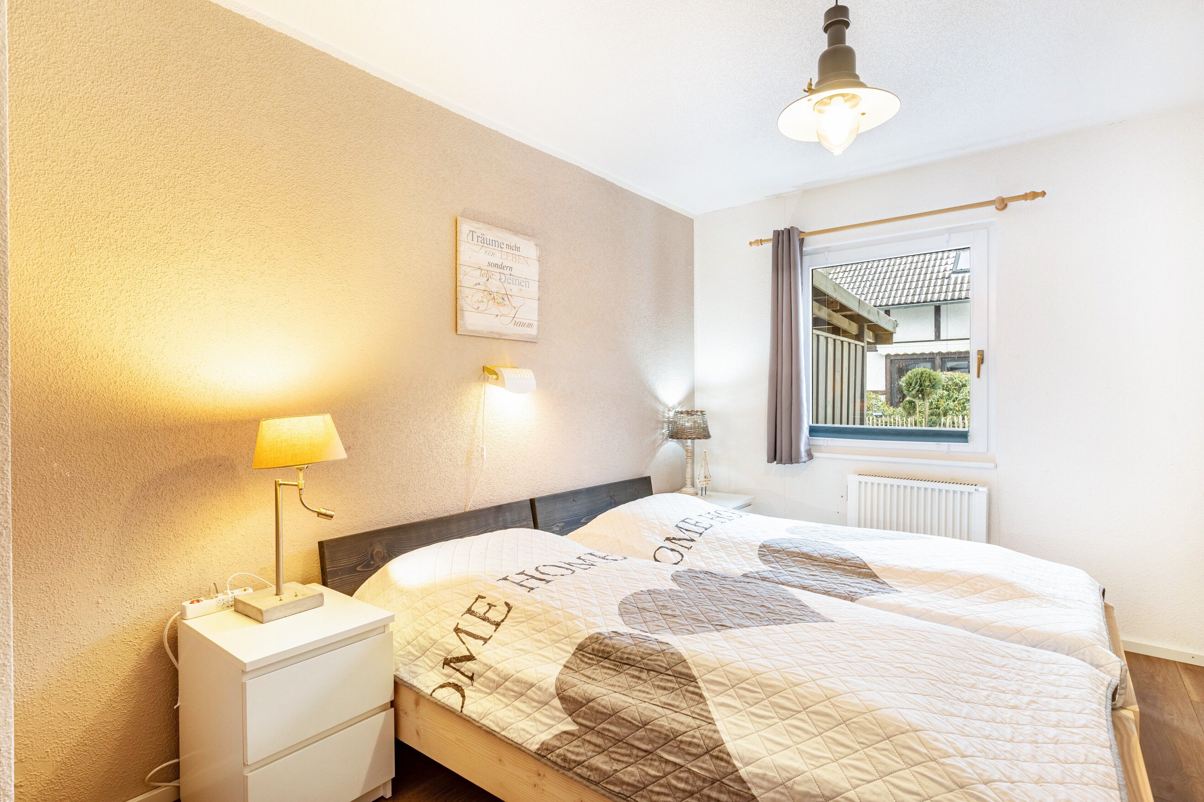 A bedroom with a bed, bedside lamps, a nightstand, a window with a view, and a ceiling light.