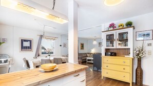 Moderni keittiö, jossa on puinen työtaso, valkoiset kaapit ja keltainen lipasto.