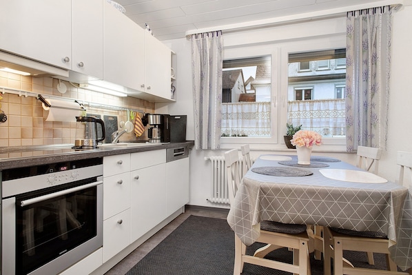 A kitchen with white cabinets, a built-in oven, and a dining area with a table set for two.
