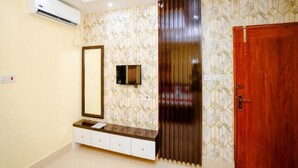 A modern bathroom with a vanity, a mirror, a wall-mounted TV, and a wooden door. - Adarsha Palace Hotel (Chuknagar)