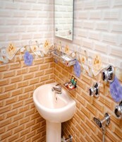Un baño con un lavamanos color beige, un espejo encima y una pared con diseño.