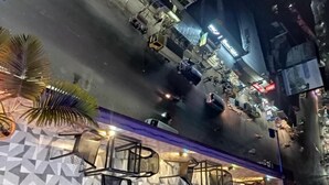 A street view at night with a restaurant featuring geometric wall patterns and outdoor seating with metal chairs. - Adarsha Palace Hotel (Chuknagar)