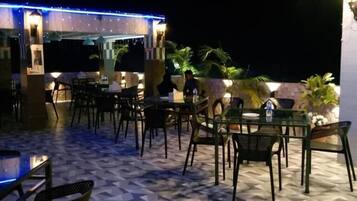 An outdoor restaurant area with tables and chairs, a patterned floor, and ambient lighting.