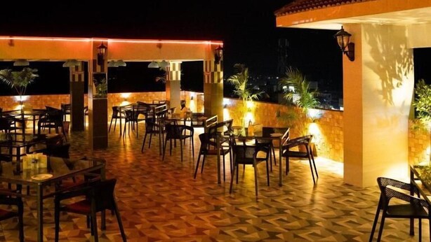 An outdoor seating area at Rooftop Restaurant with tables and chairs arranged on a patterned floor. - Adarsha Palace Hotel (Chuknagar)