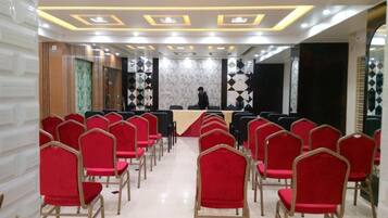 Un salón de conferencias con filas de sillas rojas, un atril y un muro con diseño.