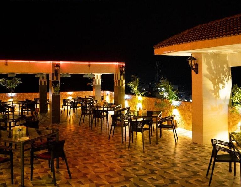 A Rooftop étteremben található szabadtéri ülőhely, ahol asztalok és székek vannak elrendezve egy mintás padlón.