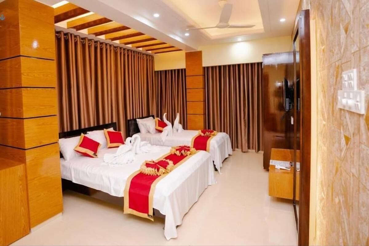 A hotel room with two beds, a TV, and a wooden accent wall.