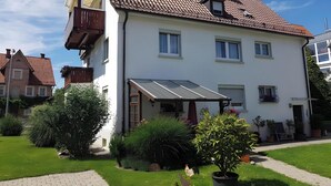 A two-story house with a tiled roof, a balcony, and a covered patio area. - Apartment 'Michael' with Balcony and Wi-Fi (Langenargen)