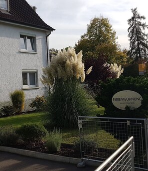A white building with a sign reading 'FERIENWOHNUNG zu vermieten' and a gated entrance.