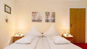 A double bed with white linens, two nightstands with lamps, and two wall-mounted paintings. - Apartment 'Michael' with Balcony and Wi-Fi (Langenargen)