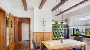 A dining area with a wooden table, chairs, and a bench. There is a green decorative wall, a white door, and a window with a view. - Apartment 'Lux' with Private Garden, Balcony and Wi-Fi (Plettenberg)