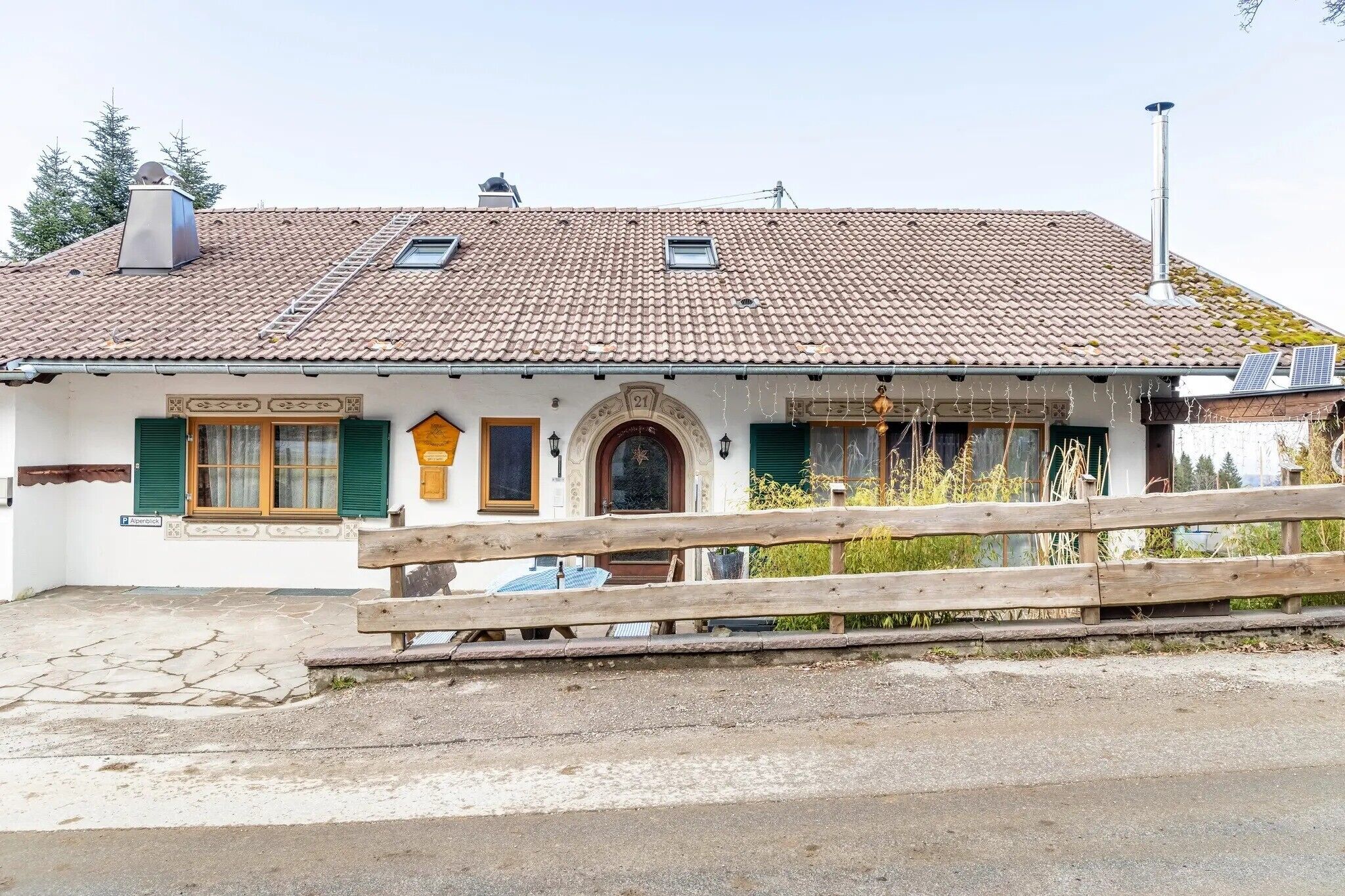 A traditional house with a tiled roof, a wooden fence, and a number 21 sign.
