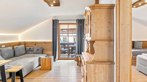 A modern living room with a wooden ceiling, a sofa, a dining table, and a view through a glass door. - Holiday Apartment "Haus Alpenquelle Seeblick" with Mountain View, Balcony & Wi-Fi (Bad Kohlgrub)