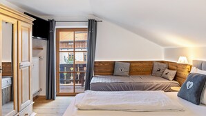 A bedroom with a bed, a wooden headboard, a window with curtains, and a view of the outside. - Holiday Apartment "Haus Alpenquelle Seeblick" with Mountain View, Balcony & Wi-Fi (Bad Kohlgrub)
