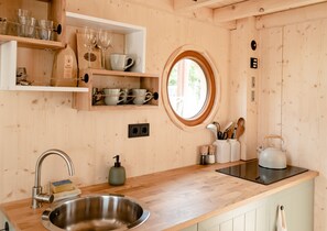 Een koelkast, een kookplaat, kookgerei, borden en bestek