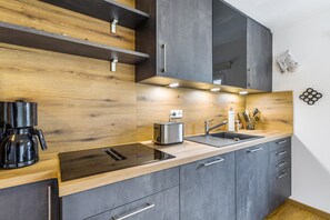 Uma cozinha moderna com bancada de madeira, eletrodomésticos embutidos e armários cinzentos.