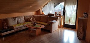 Ein gemütliches Wohnzimmer mit einer Couch, einem Couchtisch und einem Fenster mit Vorhängen.