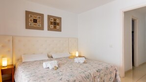 A double bed with floral bedding, two bedside tables with lamps, and two wall art pieces above the bed. - Paraiso Royal I, Sunny Terrace & Heated Pool (Playa de las Américas)