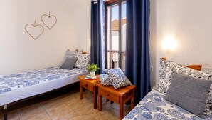 A cozy room with two single beds, a small wooden table, and a potted plant. - 395 Lovely Duplex Parque Santiago II (Playa de las Américas)