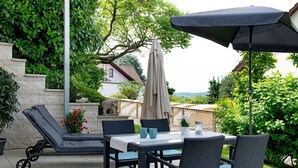 A patio with a table, chairs, a lounge chair, and an umbrella.