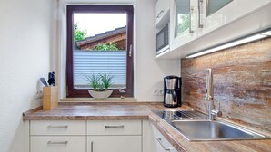 A compact kitchen with a window, a coffee maker, and a sink.