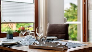 A dining table set with plates, cutlery, and glasses, a decorative sign reading 'Home,' and a window with a view of greenery.