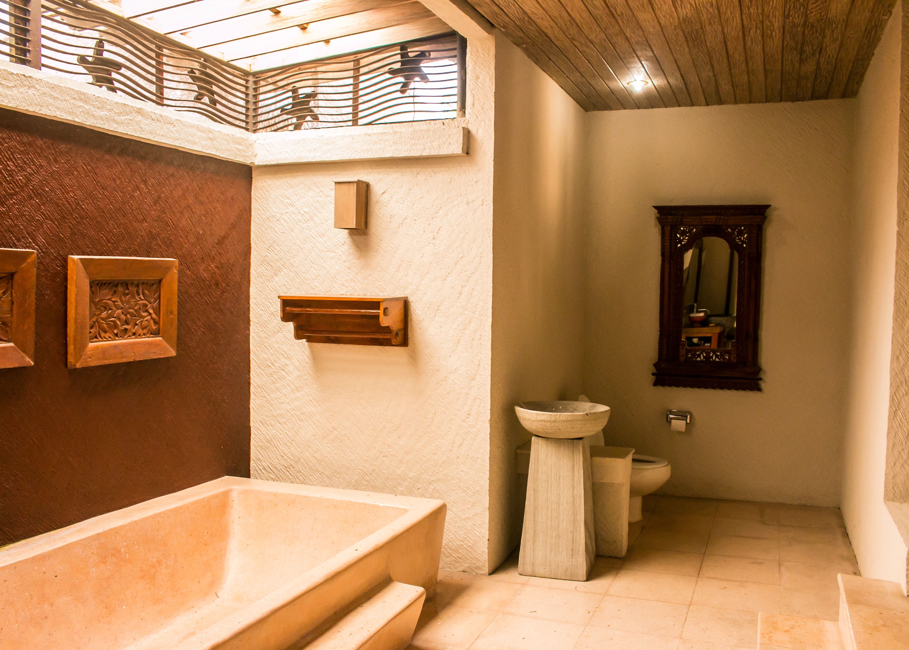 A bathroom with a freestanding bathtub, a pedestal sink, and a wooden-framed mirror.