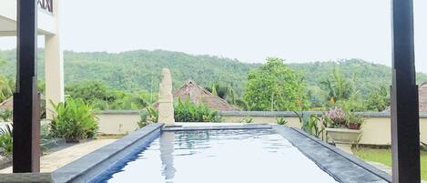 Una piscina en la azotea con vistas a un paisaje verde exuberante y una colina distante.
