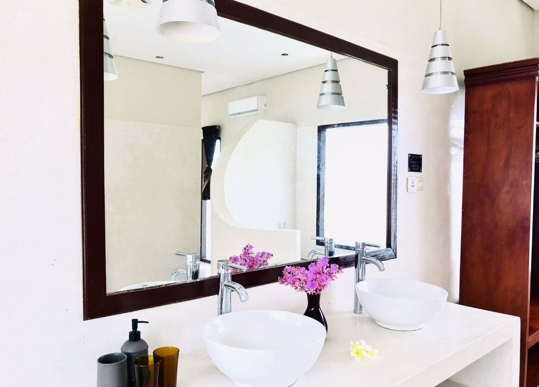 A bathroom with two sinks, a large mirror, and pendant lights.