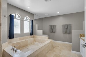 A modern bathroom with a large bathtub, a sink, and a shower.
