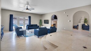 A spacious living area with a curved seating arrangement, a ceiling fan, and a large TV mounted on the wall. - Grand Casa (Las Vegas)