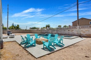 A backyard with a swimming pool, outdoor seating, and a barbecue area.