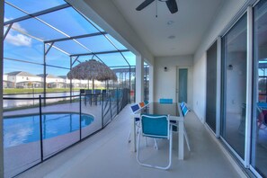 A covered outdoor area with a pool, seating, and a thatched umbrella.
