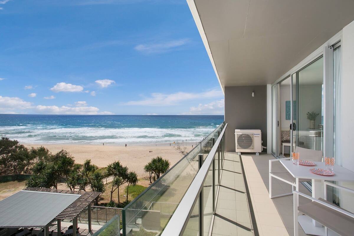 A balcony with a view of the beach and ocean.