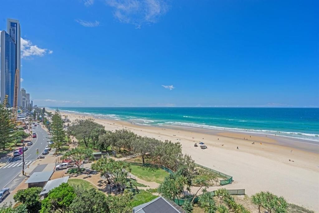 A coastal cityscape with a beach, tall buildings, and a clear blue sky.