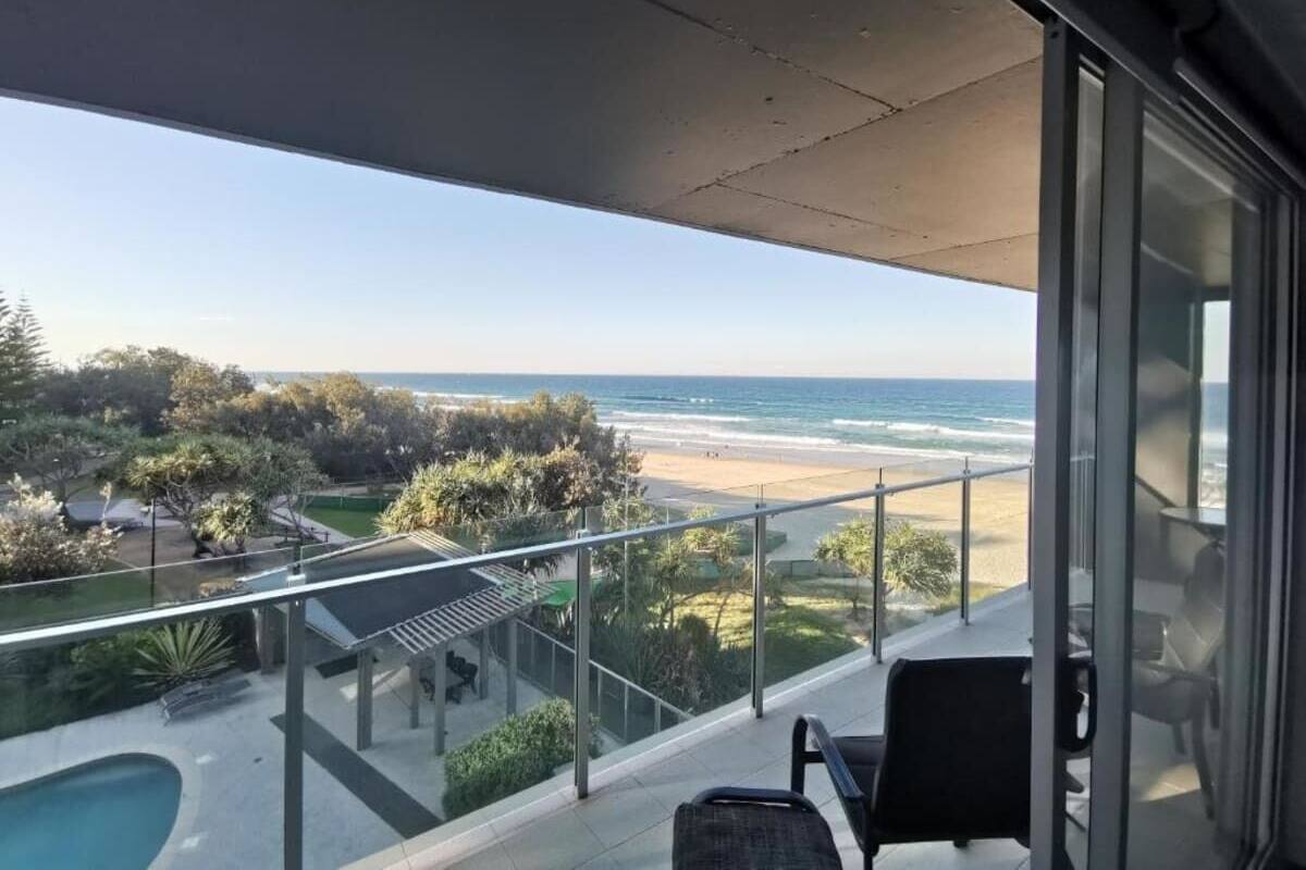 A balcony with a view of the beach and ocean.