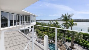 Un edificio moderno con ventanas amplias, un balcón con piscina y vista al agua.