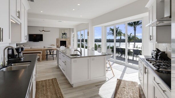 Una cocina moderna con una isla grande, muebles blancos y vistas al océano.