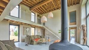 A spacious living area with a high ceiling, a staircase, and a large black sculpture. - Exceptionnel farm house with pool and paddle court (Mareuil en Périgord)