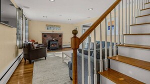 A living room with a fireplace, a staircase, and a sofa. - Paws and Pines Retreat! (Ellsworth)