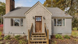 A two-story house with a stone facade, a wooden front door, and a satellite dish. - Paws and Pines Retreat! (Ellsworth)