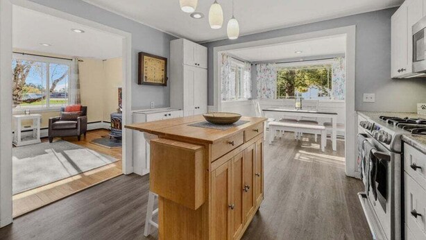 A modern kitchen with a central island, white cabinetry, and pendant lighting. - Paws and Pines Retreat! (Ellsworth)