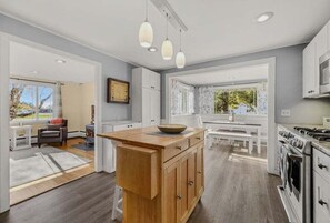 A modern kitchen with a central island, white cabinetry, and pendant lighting. - Paws and Pines Retreat! (Ellsworth)