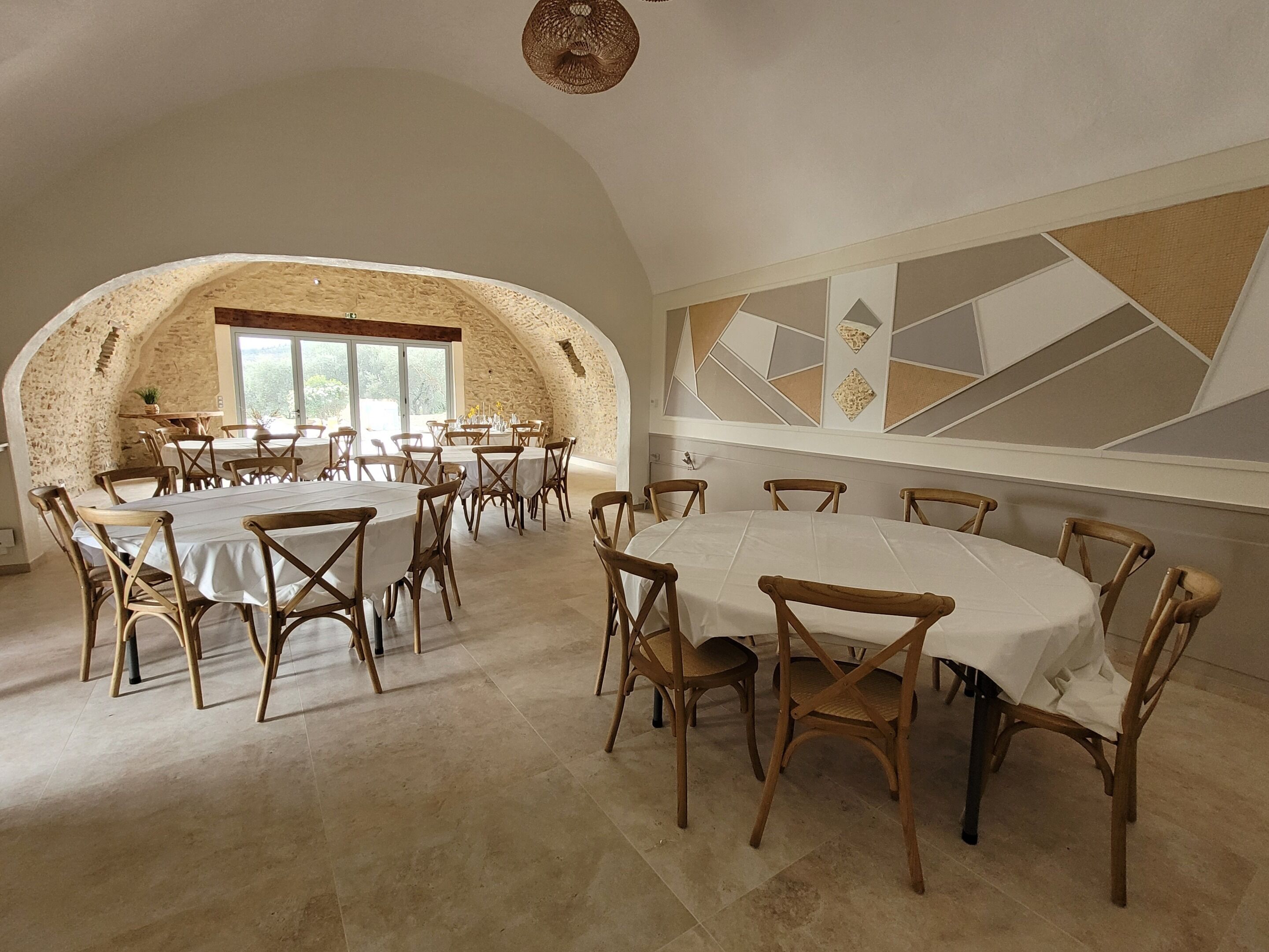 A spacious dining area with high tables and wooden chairs, a stone wall, and a large window.