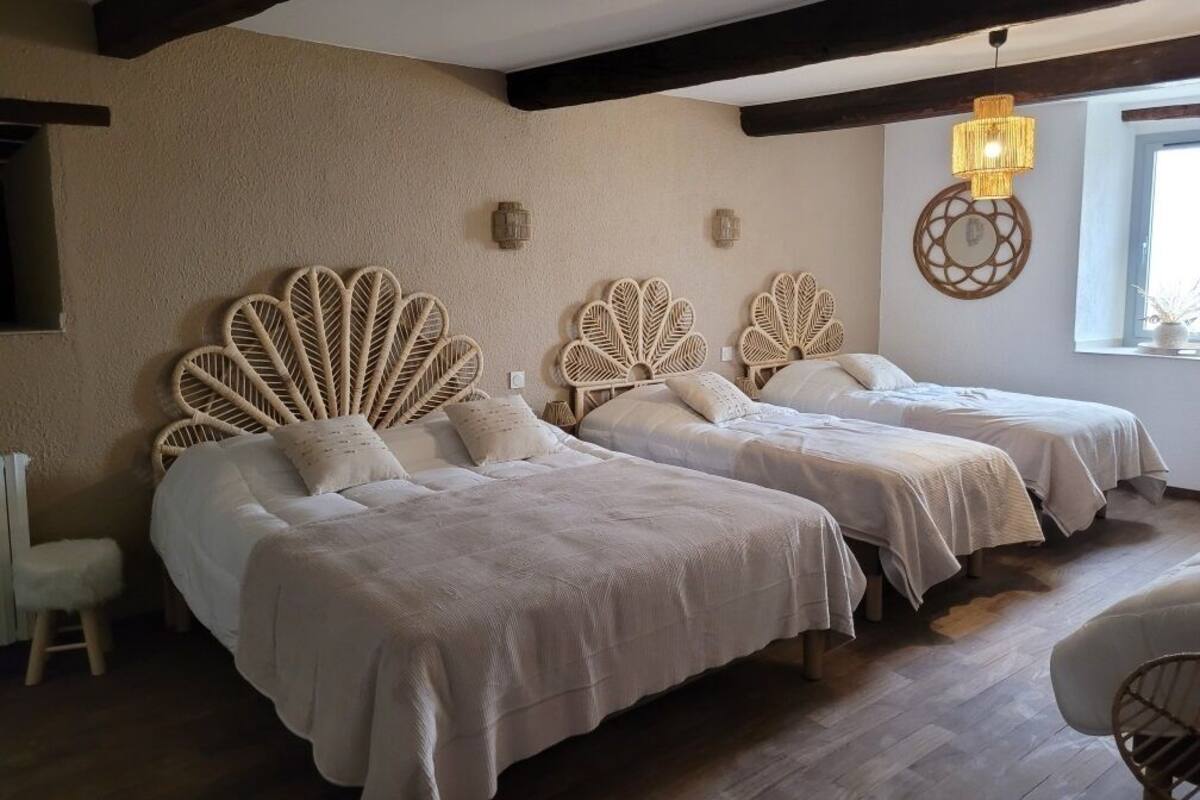 A room with two beds, each with a unique woven headboard, a hanging light fixture, and a window providing natural light.